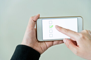 Closeup of hand holding smartphone with vote button on the screen