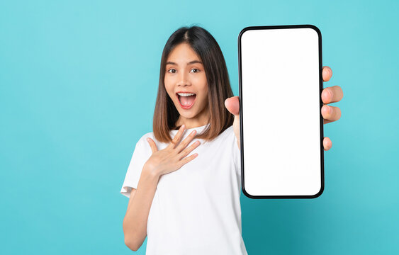 Studio shot of Beautiful Asian woman holding smartphone mockup of blank screen and smiling on blue background.