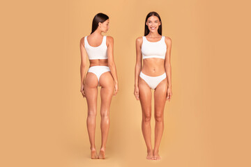 Full length shot of front and back view of slim lady posing on beige background, demonstrating...