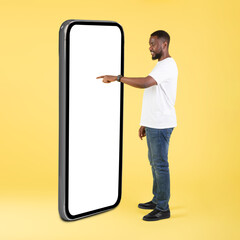 African guy using big phone touching blank screen in studio