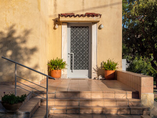 Classic design house pale ocher front and external entrance door, in calm Athens suburbs, Greece.