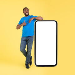 African Guy Near Large Phone Gesturing Thumbs Up, Yellow Background