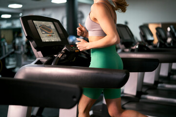 Part of caucasian woman running on treadmill at fitness center