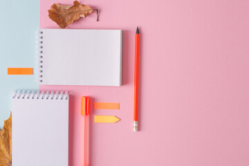Blank white notebooks on a pink-blue background with orange pencils and markers. Hi School