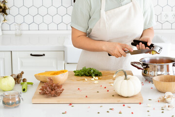 Woman hands cleaning a garlic press in modern white kitchen. Garlic-pressed. Homemade autumn pumpkin soup recipe
