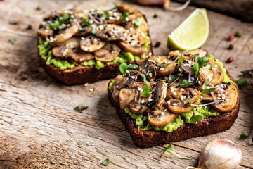 Toast avocado, mushrooms and microgreen whole grain sandwich. Decorated with sesame. Vegetarian food. Vegan menu. Food recipe background