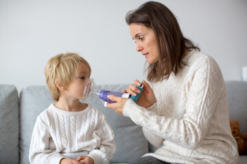 Mother, helping little toddler child with inhaler with spacer - obrazy, fototapety, plakaty