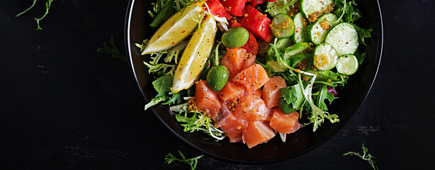 Ketogenic, keto or paleo diet lunch bowl with salted salmon fish, lemon, cucumber, olives, tomatoes, green lettuce salad and honey mustard dressing. Healthy food trend. Top view, banner