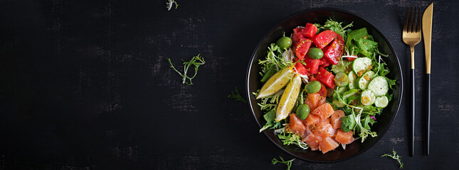 Ketogenic, keto or paleo diet lunch bowl with salted salmon fish, lemon, cucumber, olives, tomatoes, green lettuce salad and honey mustard dressing. Healthy food trend. Top view, banner