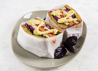 Sandwich with chicken fillet, red cabbage and sauce, wrapped in paper. Take along.