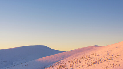 Fototapeta na wymiar Winter mountain landscape. Sunset over the mountain slopes covered with snow.
