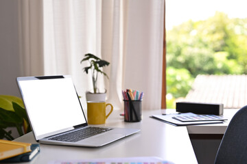 Creative working desk with laptop computer, coffee cup, stationery and potted plant