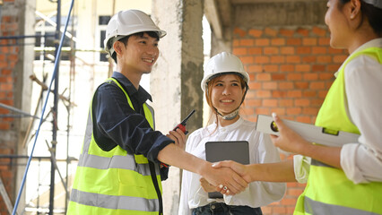 Smiling civil engineer and investor shaking hands for architectural project, agreement success in working site