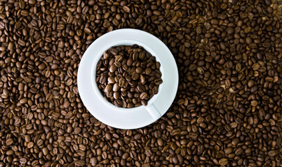 Coffee beans in cup and on table for background