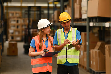 Imaged of warehouse worker standing between retail warehouse full of shelves with goods and using digital tablet