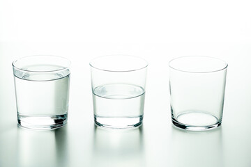 Three crystal glasses, one full of liquid, one half-full and one empty - concept of quantity and capacity