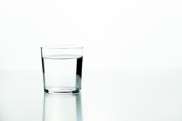 Glass tumbler filled with water on a white background with a minimalist concept and plenty of copy space.