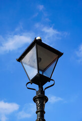 Fototapeta na wymiar ornate street lamp in blue sky. Decorative vintage lantern in town. 