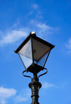 ornate street lamp in blue sky. Decorative vintage lantern in town. 