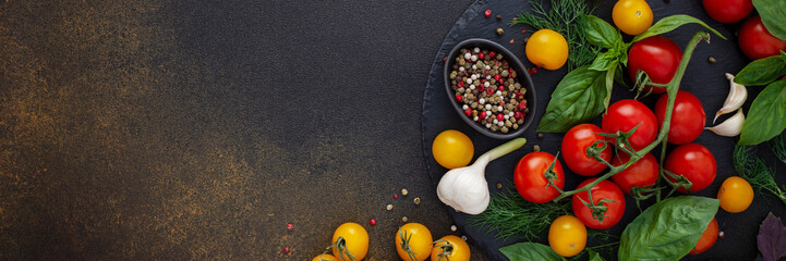 Food banner, fresh ripe red and yellow tomatoes, spices and basil leaves, garlic and green onions on dark board, healthy food concept, copy space, top view