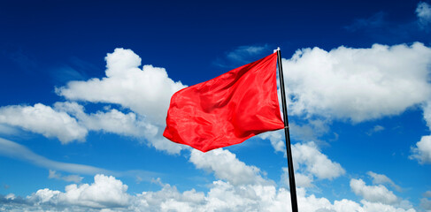 Red flag waving against blue sky