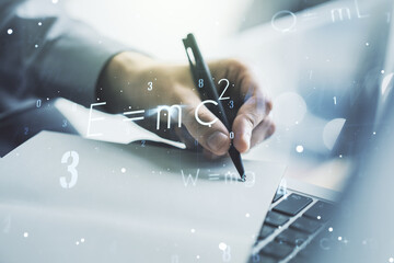 Creative scientific formula concept with hand writing in notebook on background with laptop. Multiexposure