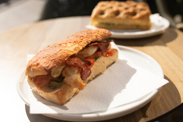 Fresh sandwiches with ham, cheese, bacon, tomatoes, lettuce, cucumbers and onions on wooden background.
