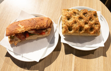 Fresh sandwiches with ham, cheese, bacon, tomatoes, lettuce, cucumbers and onions on wooden background.