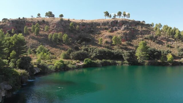 Drone revealing shore of turquoise Laguna Colgada in a dry environment (Lagunas de Ruidera, Ciudad Real)