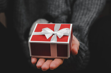 Gift box in female hands, close-up. Woman holding a red gift box