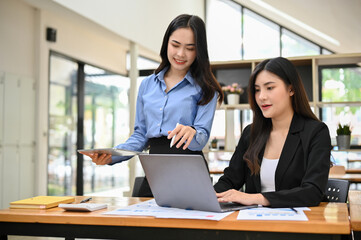 Fototapeta premium Asian businesswomen or financial analysts working on their financial and sales analysis together
