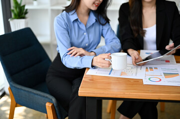 cropped image, an attractive Asian female manager sipping morning coffee during the meeting.