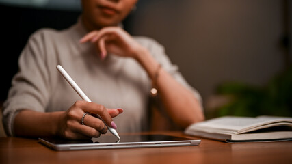 Elegant Asian businesswoman using a digital tablet to take notes and plan her work.