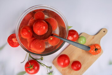 a lot of blanched tomatoes in a bowl with water, ready for peeling