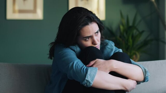 Video of depressed woman sitting on the coach at home.