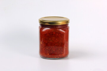 glass jar with boiled red tomato sauce on a white background