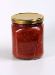 glass jar with boiled red tomato sauce on a white background
