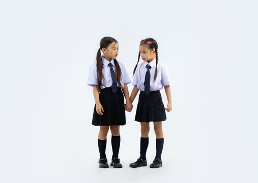 Primary and junior school girl in student uniform posing standing full length on white wall background. Back to school kids.