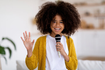 Cute black preteen girl holding microphone and waving