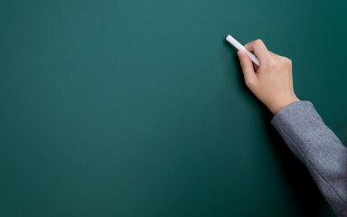 Naklejka premium Businesswoman hand writing chalk on blackboard