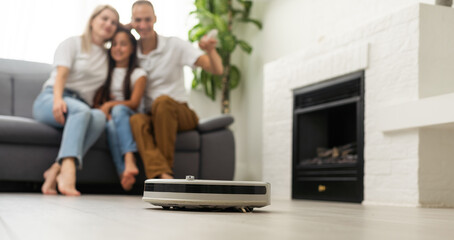 Family resting while robotic vacuum cleaner doing its work at home