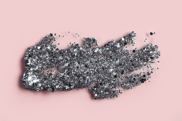 Silver glitter cosmetic product smear on pink background. Eye shadow, lip gloss and face glitter...