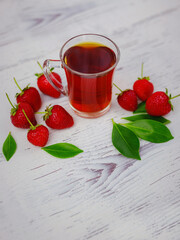 Fresh organic strawberries and black tea in glass cup , over white background. Vegetarian healthy food concept.
