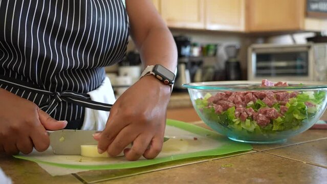 Cutting a round of mild, white cheese to add to a chopped salad - ANTIPASTO SALAD SERIES