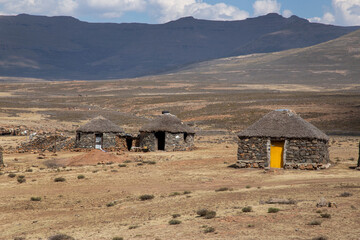 Mountain side with traditional African Lesotho huts rural out of focus with grain