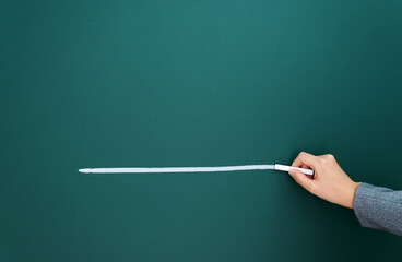 Woman hand chalk drawing white line on blackboard