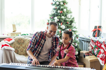 father and daughter playing the piano at christmas