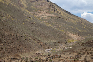 Mountain side with traditional African Lesotho huts rural out of focus with grain