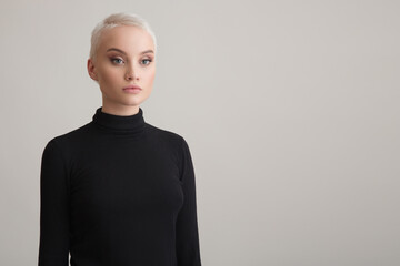 Portrait of a beautiful blonde girl with a short haircut. Grey background.