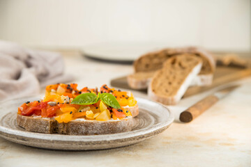 Homemade vegetable bruschetta on a handmade ceramic plate in warm colors, horizontal orientation, side view